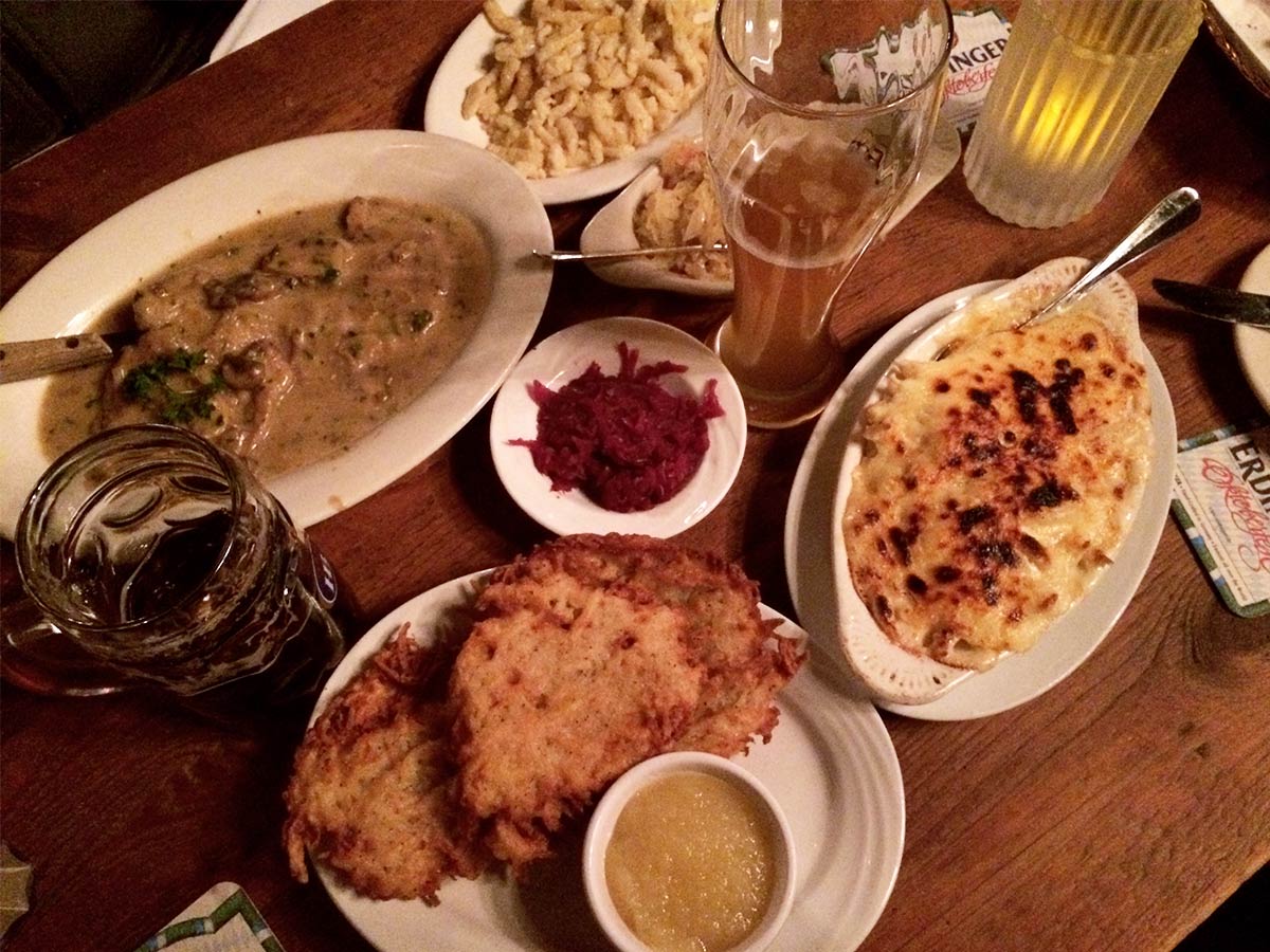 nyc best restaurant a table is filled with German food like spatzel, schnitzel and potato pancakes