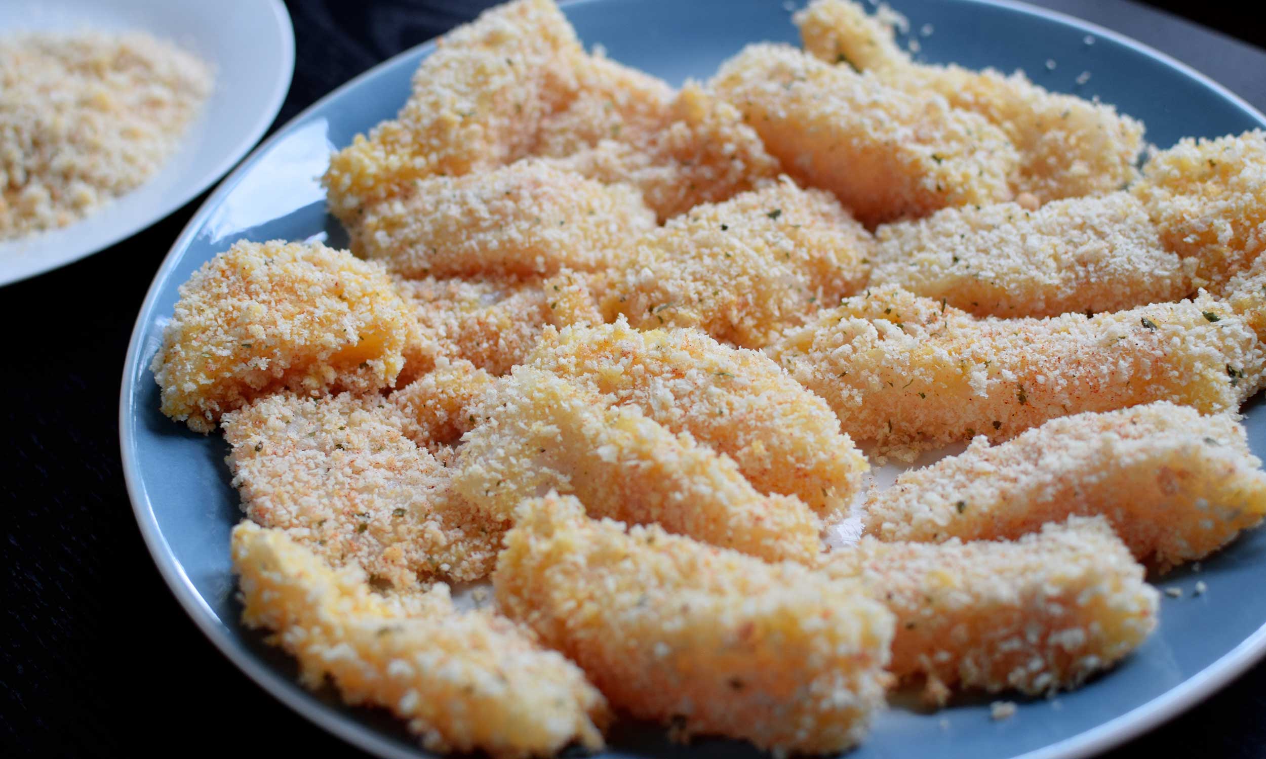 breaded cod for baja fish tacos shows cod cut into 1 by 3 inch rectangles, battered in egg and panko before frying